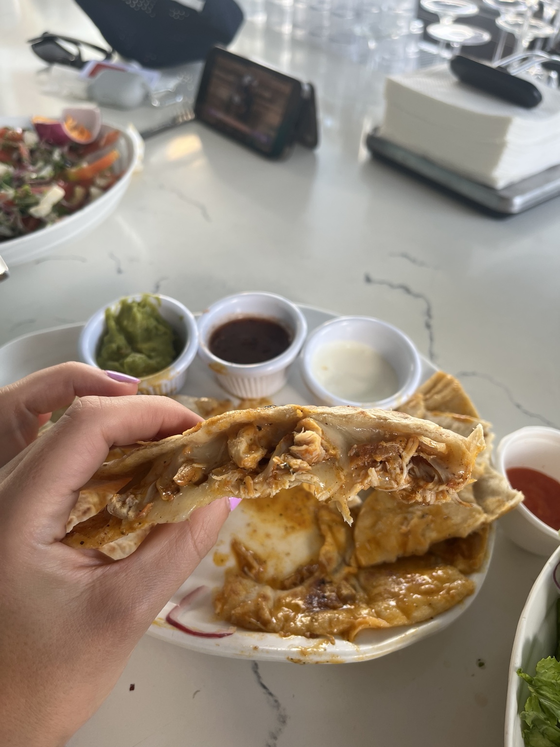 Close-up of crisp flatbread filled with shredded chicken and melted cheese