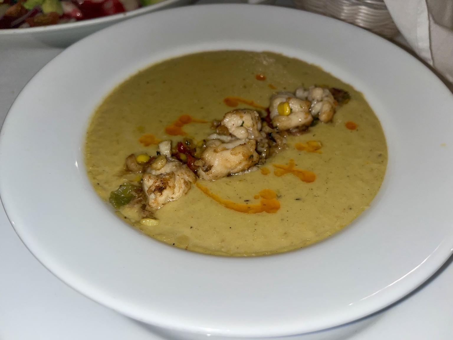 Creamy golden seafood soup with vegetables and chile oil
