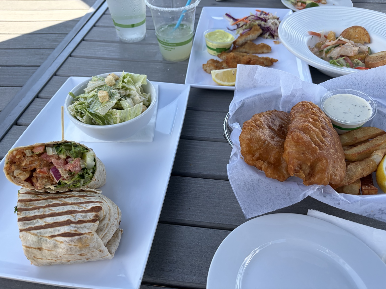 Battered fish and chips served beside a grilled wrap and salad