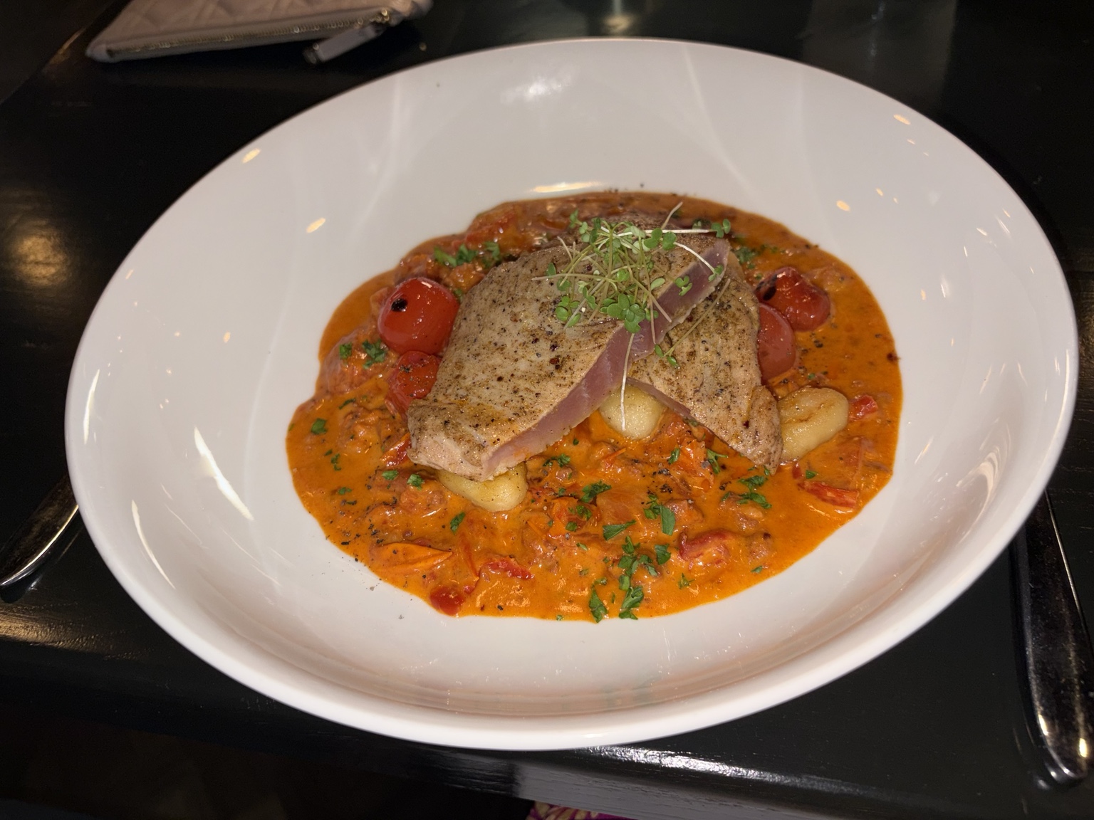 Pepper-crusted seared tuna over dumplings and tomato sauce