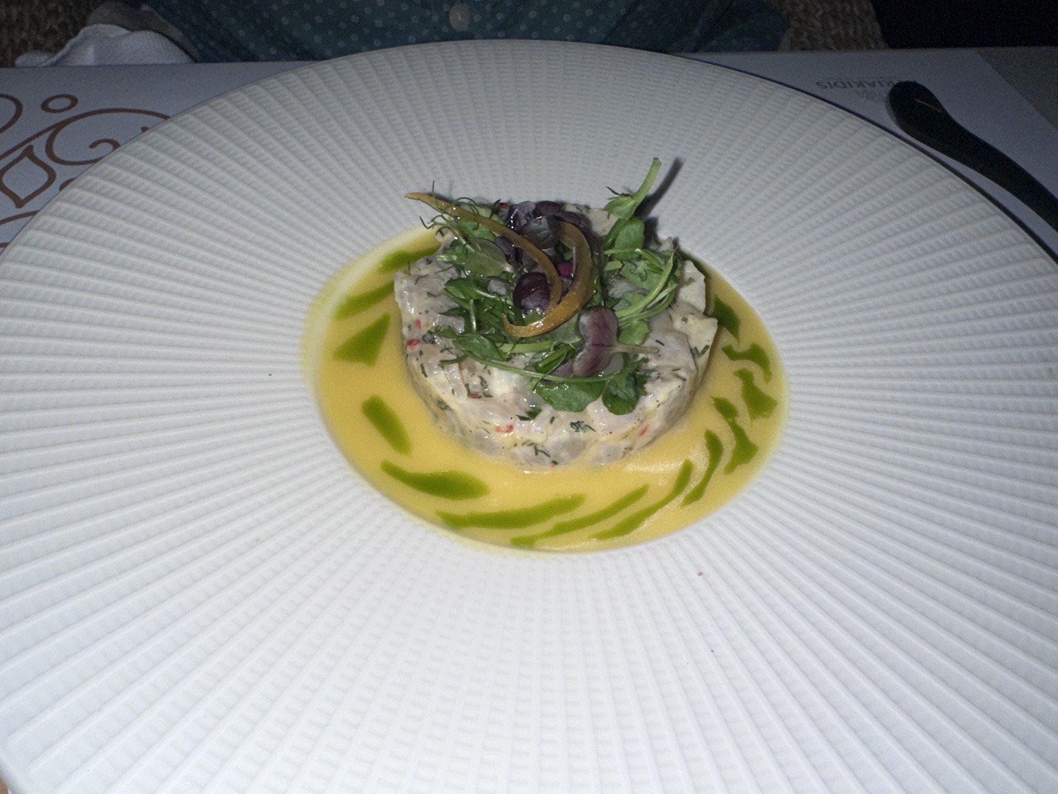 Fish tartare with herbs in yellow citrus sauce and green herb oil