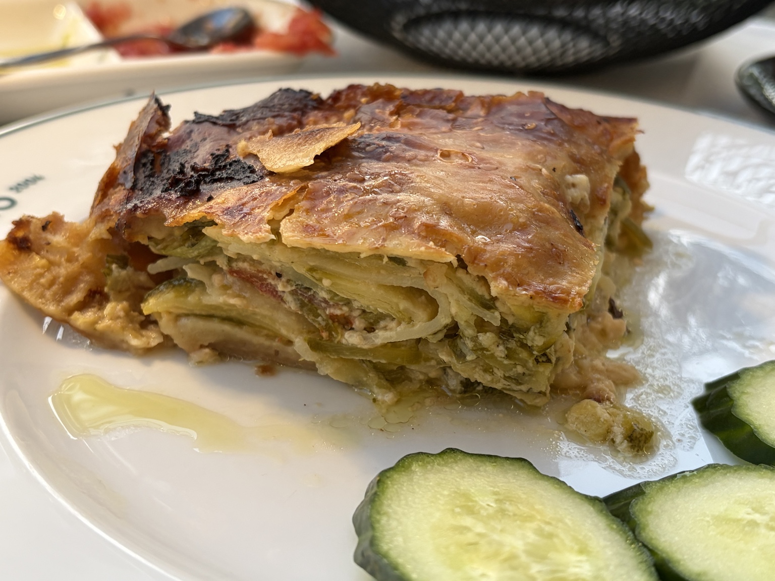 Flaky layered savory pie filled with greens, tomato and soft cheese