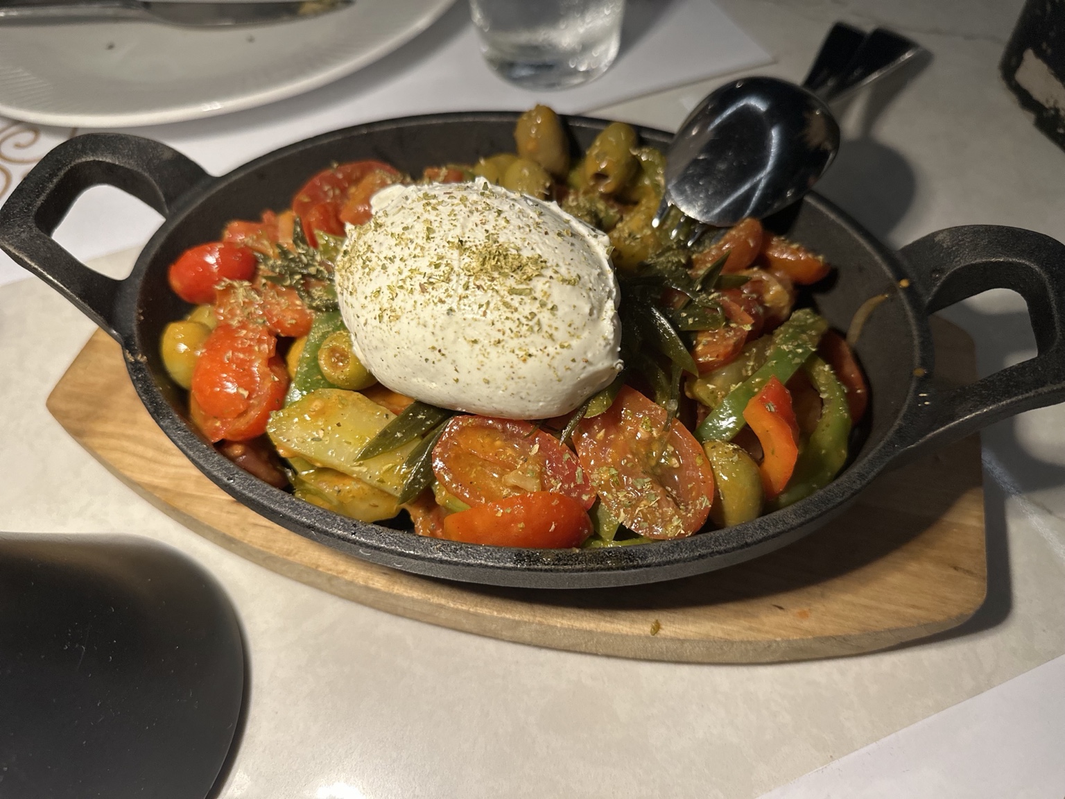 Warm tomatoes, peppers and olives topped with soft herb-dusted cheese