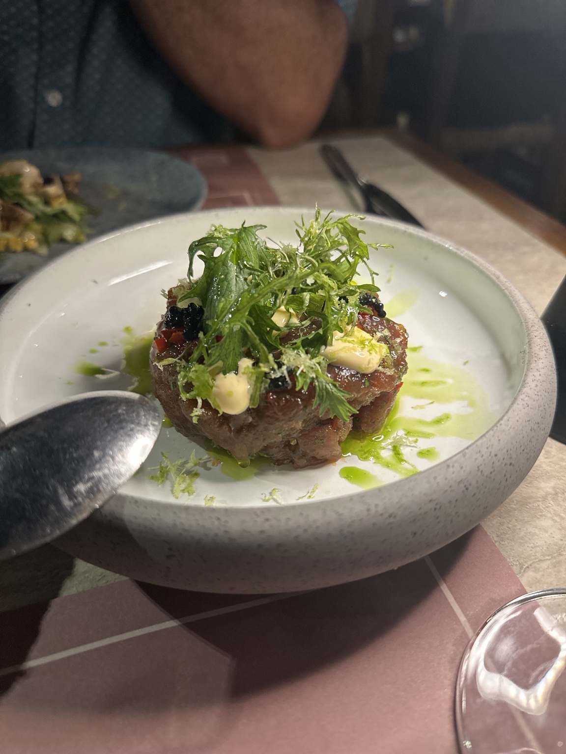 Tuna tartare topped with greens, creamy sauce, herb oil and dark roe