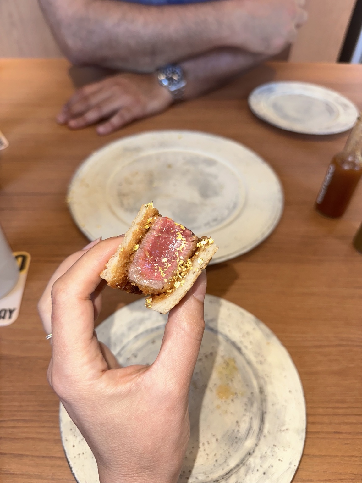 Hand holding a thick beef katsu sandwich with a rosy center
