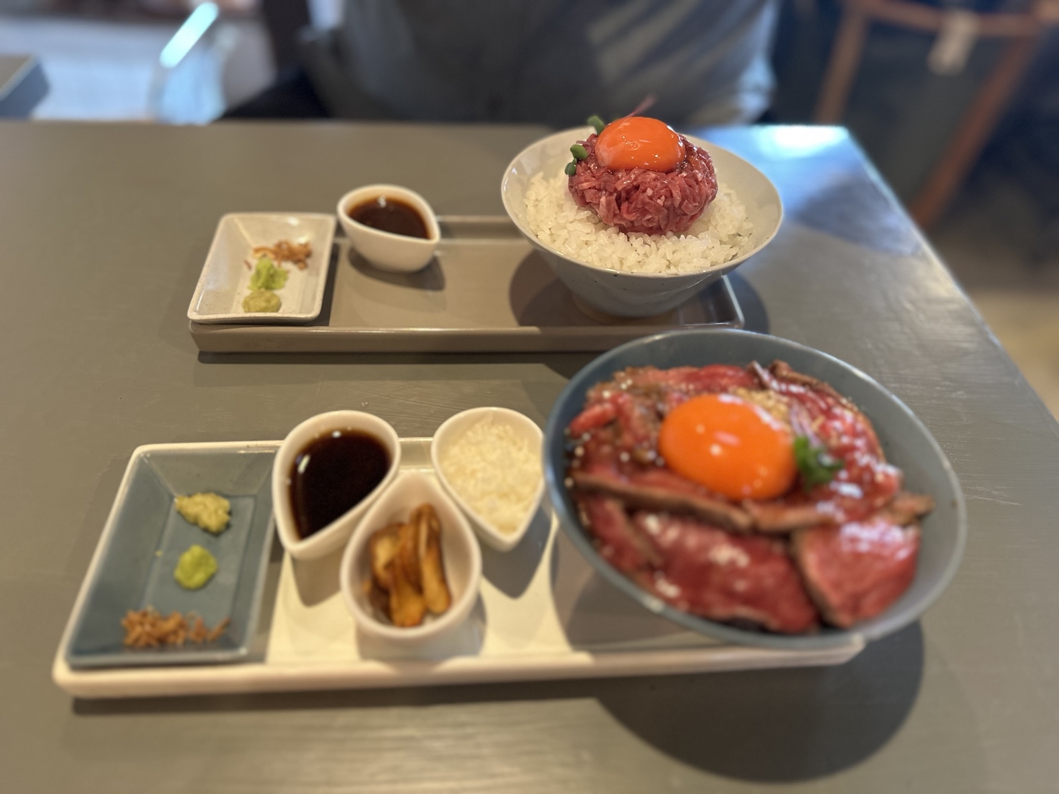 Two rice bowls topped with beef and egg yolks