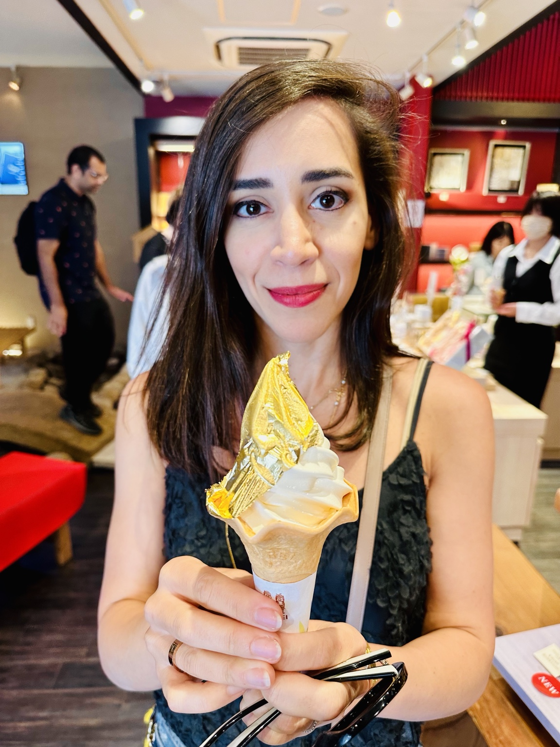 Woman holding a soft-serve ice cream cone covered with gold leaf