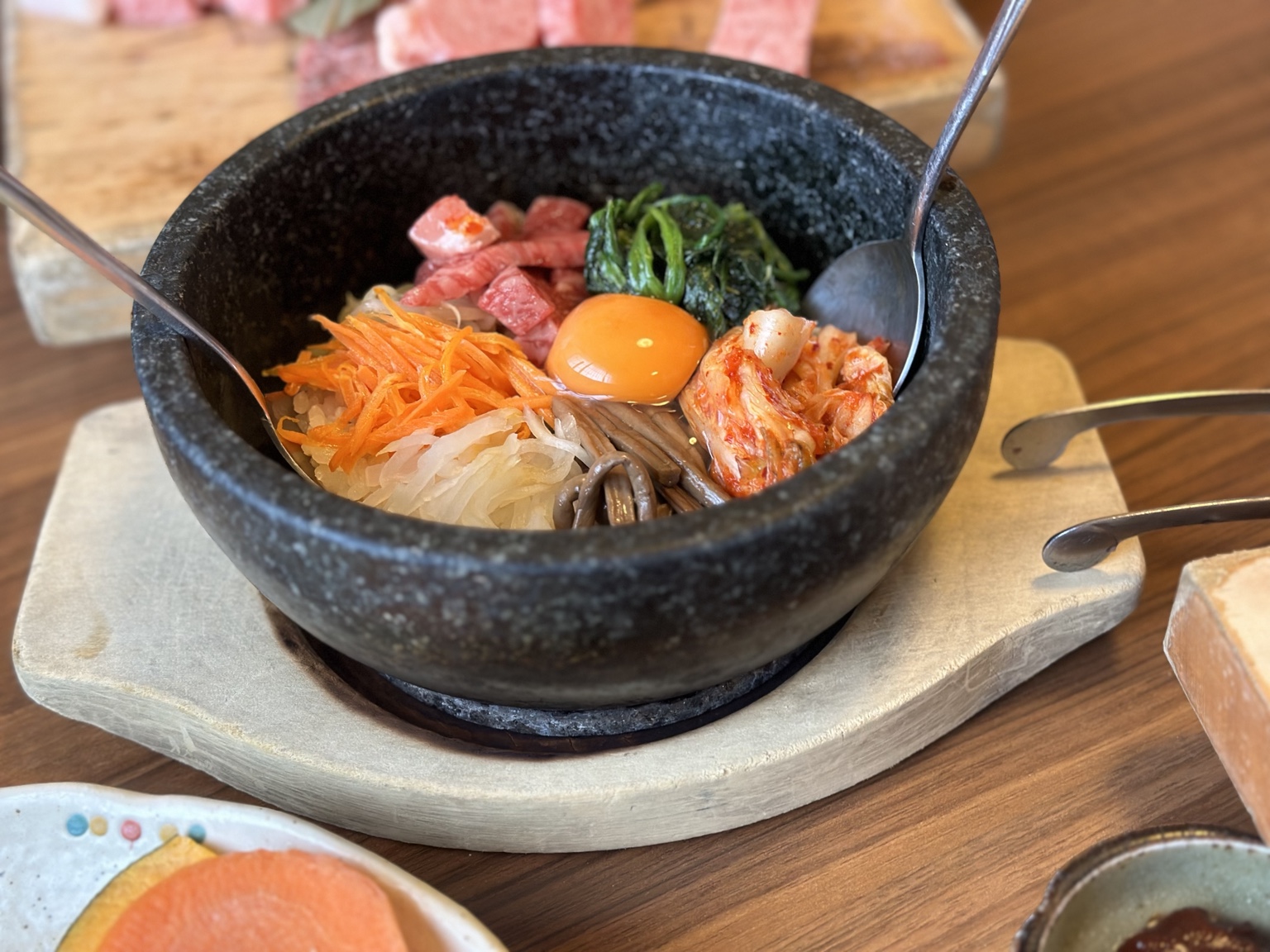 Stone bowl of rice with beef, egg yolk, kimchi and vegetables