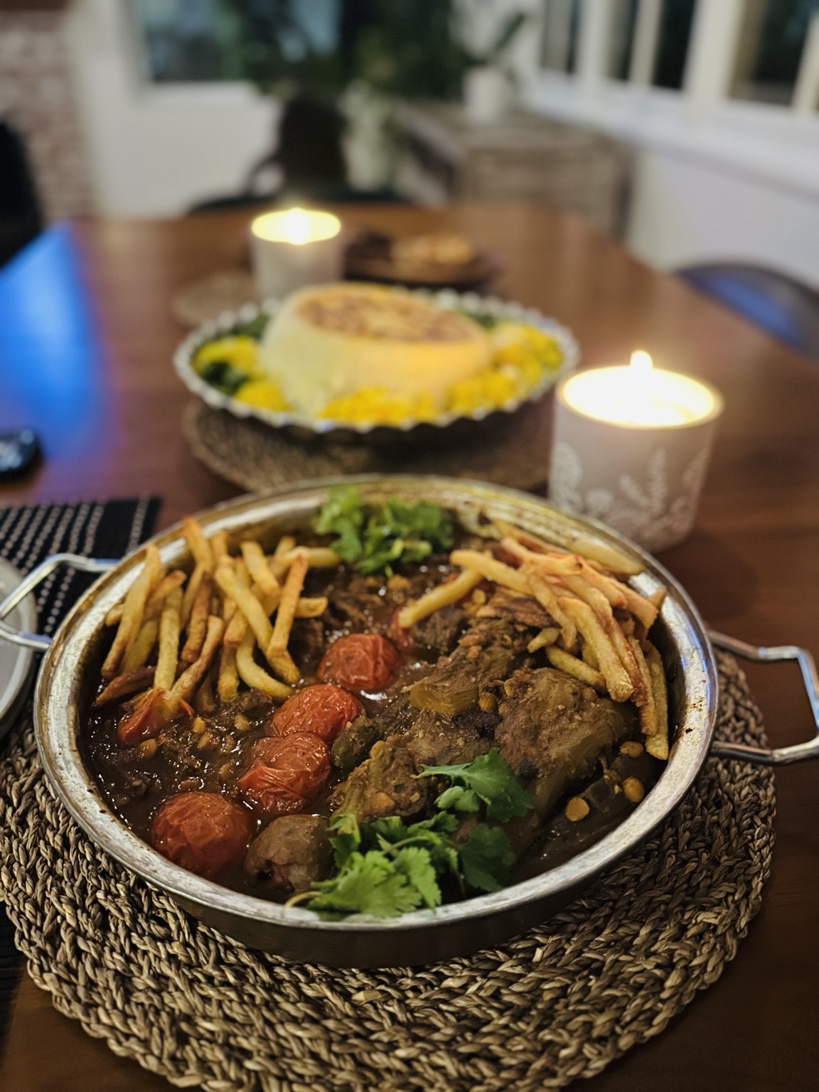 Slow-cooked meat in tomato sauce topped with fries, roasted tomatoes and herbs