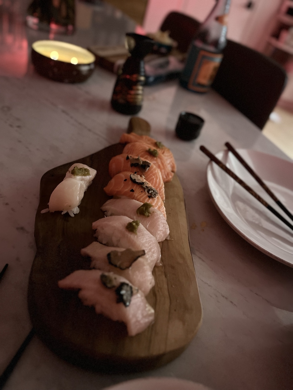 Homemade salmon and white-fish nigiri arranged on a wooden board