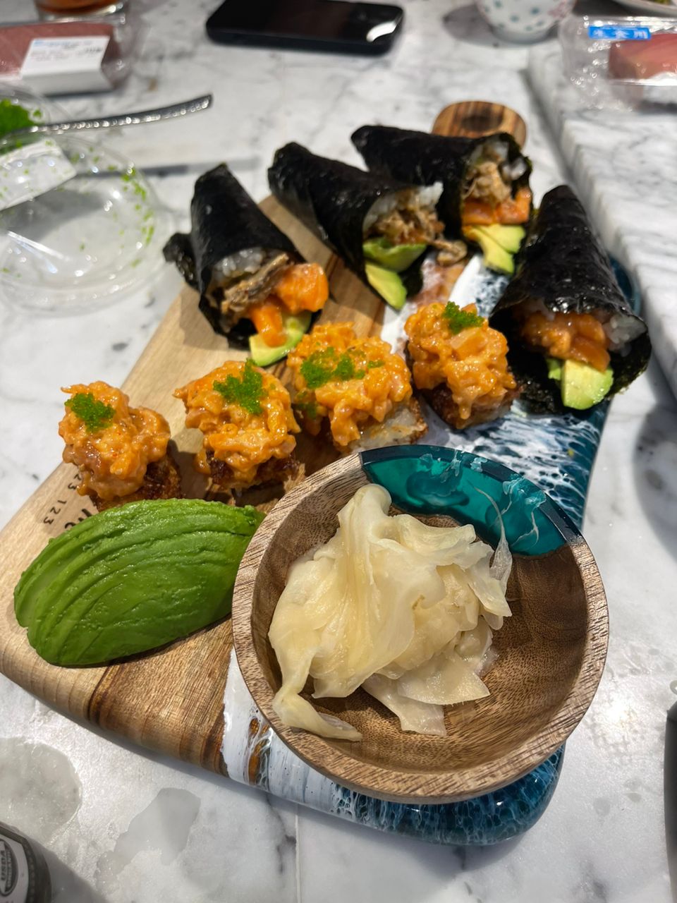 Homemade sushi hand rolls and rice bites with avocado, salmon and pickled ginger
